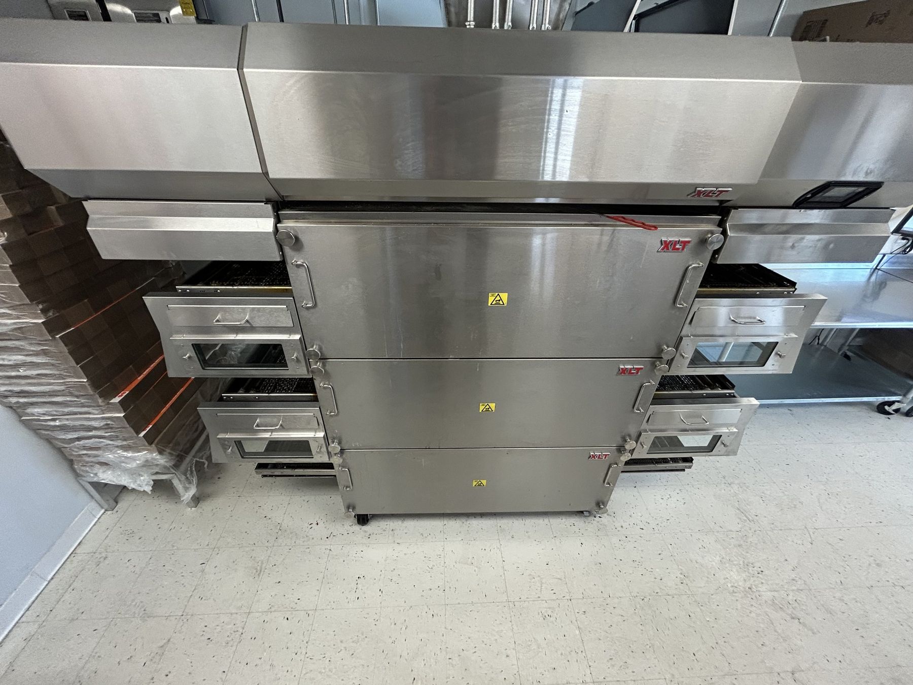 Stacked XLT conveyor ovens under a stainless exhaust hood in a commercial kitchen in Cedar City, Utah